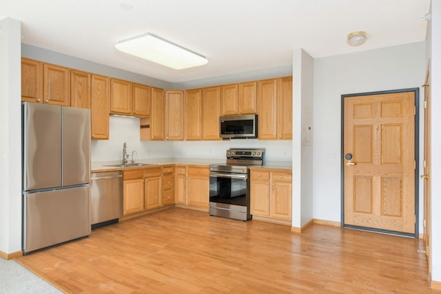 kitchen with light brown cabinets, stainless steel appliances, light hardwood / wood-style flooring, and sink