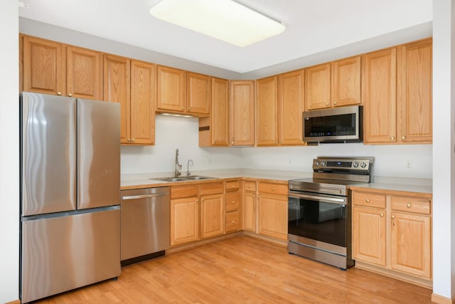 kitchen with light brown cabinetry, sink, light wood-type flooring, and appliances with stainless steel finishes