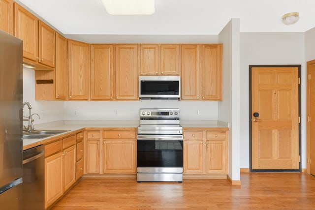 kitchen with appliances with stainless steel finishes, light wood-type flooring, light brown cabinetry, and sink