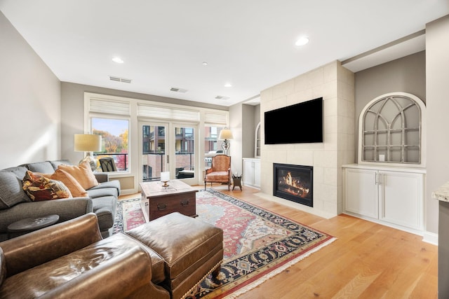 living room featuring a tile fireplace and light hardwood / wood-style floors