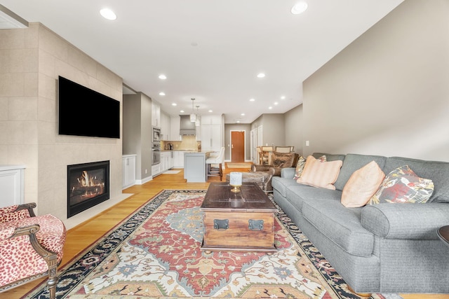 living room featuring a tile fireplace and light hardwood / wood-style floors