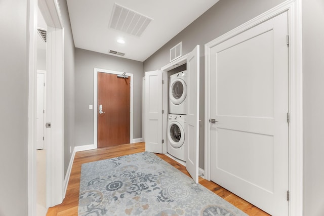 washroom featuring stacked washing maching and dryer and light hardwood / wood-style floors