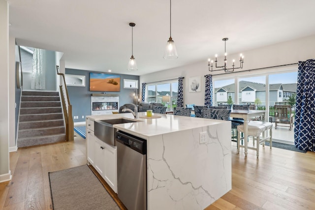 kitchen featuring light stone countertops, white cabinets, dishwasher, hanging light fixtures, and an island with sink