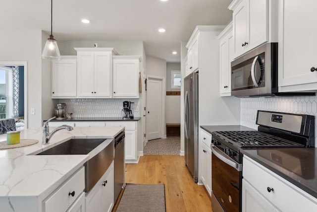 kitchen with white cabinets, hanging light fixtures, and appliances with stainless steel finishes