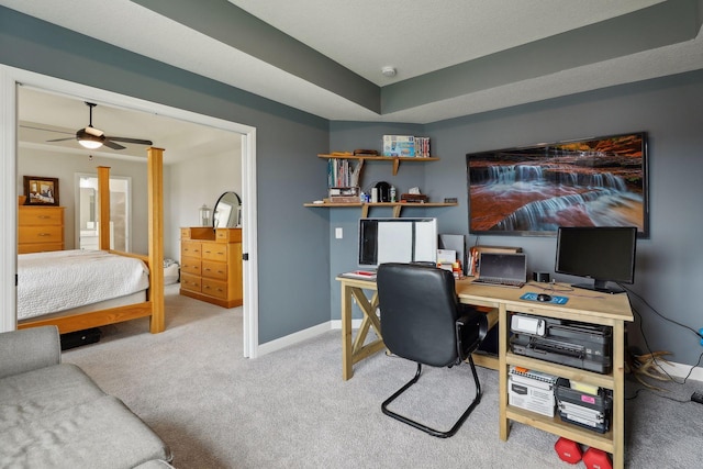 home office featuring a tray ceiling, ceiling fan, and light carpet