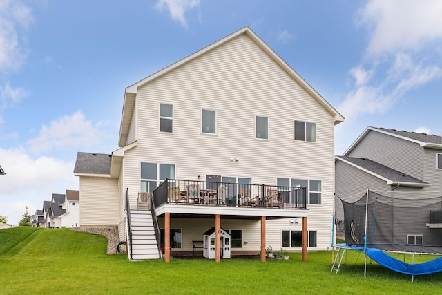 back of house with a lawn, a wooden deck, and a trampoline