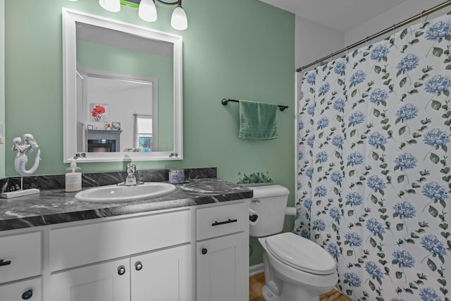 full bath featuring a glass covered fireplace, a shower with shower curtain, vanity, and toilet