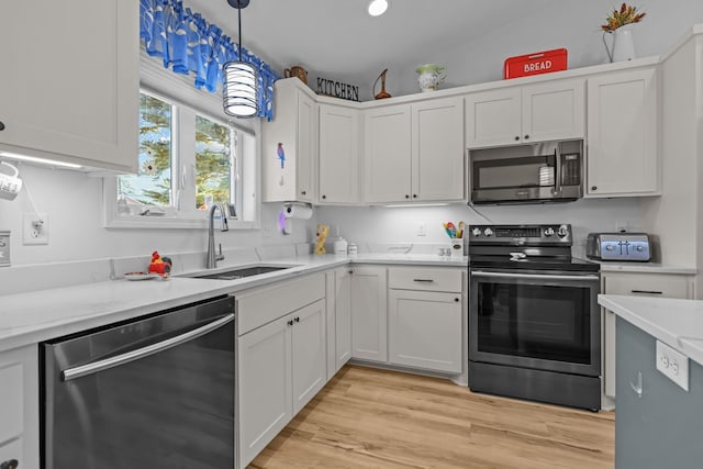 kitchen featuring a sink, pendant lighting, white cabinetry, light countertops, and appliances with stainless steel finishes