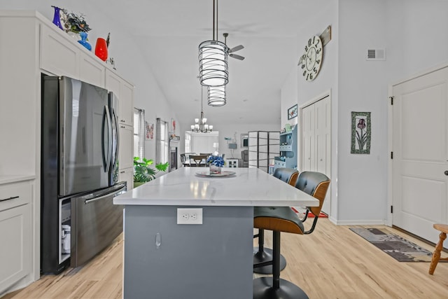 kitchen with a kitchen island, a kitchen bar, lofted ceiling, visible vents, and freestanding refrigerator