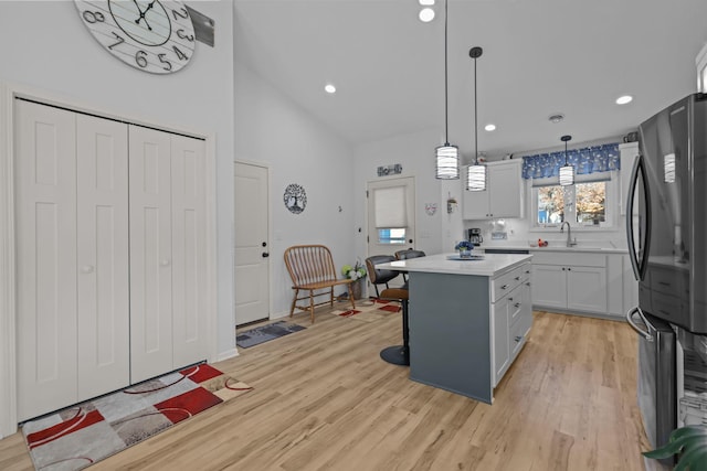 kitchen featuring light countertops, freestanding refrigerator, light wood-type flooring, a center island, and a breakfast bar area