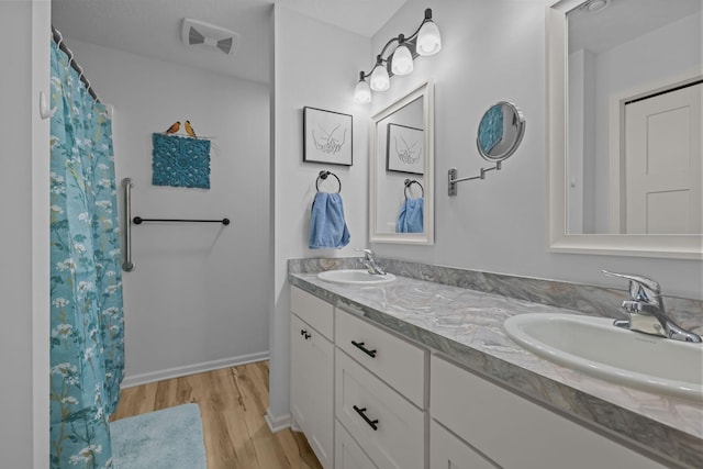 bathroom with visible vents, wood finished floors, a sink, and double vanity