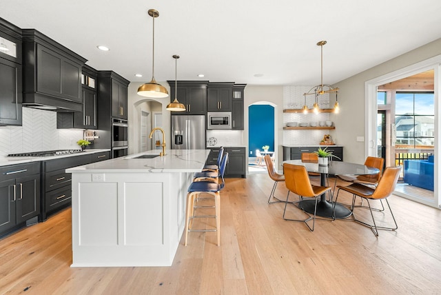 kitchen with appliances with stainless steel finishes, sink, a center island with sink, and decorative light fixtures