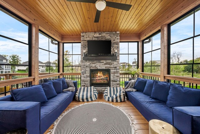 sunroom with wood ceiling, ceiling fan, and an outdoor stone fireplace