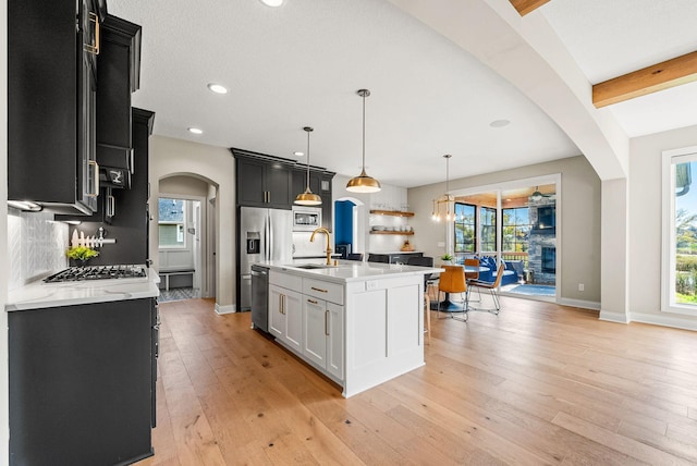 kitchen with sink, dishwasher, hanging light fixtures, tasteful backsplash, and a center island with sink