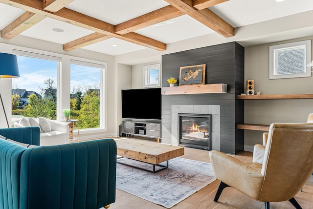 living room with coffered ceiling, beam ceiling, light hardwood / wood-style floors, and a large fireplace