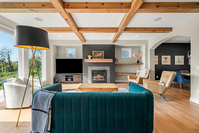 living room with beam ceiling, coffered ceiling, a fireplace, and light hardwood / wood-style floors