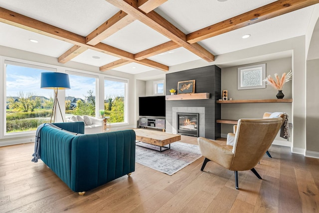 living room featuring beamed ceiling, coffered ceiling, a large fireplace, and hardwood / wood-style floors