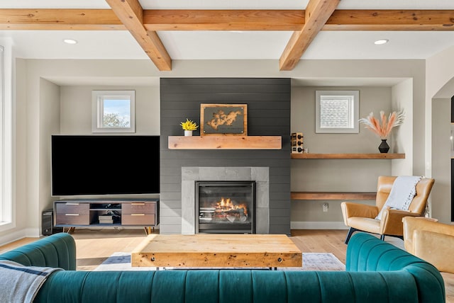 living room with light hardwood / wood-style flooring, a fireplace, and beamed ceiling