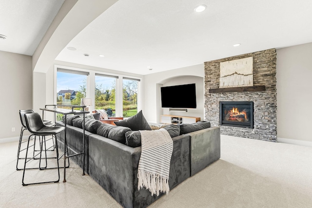 living room with a stone fireplace and light colored carpet