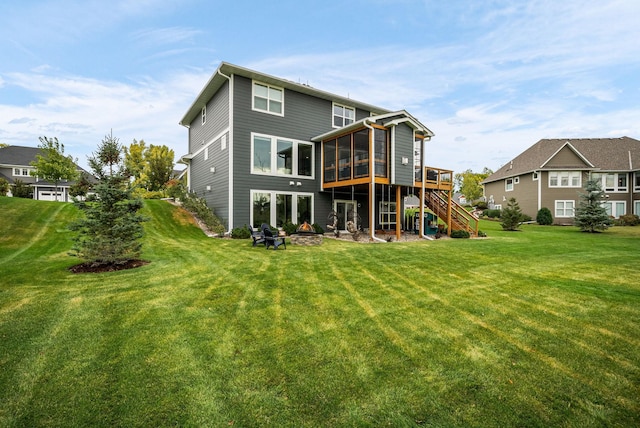 back of property featuring a wooden deck, a yard, and a sunroom