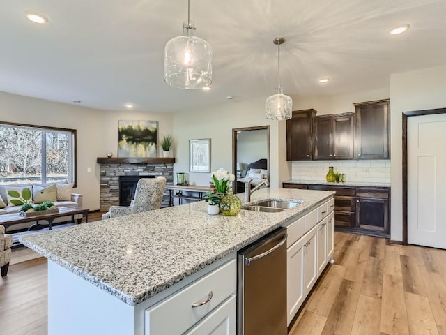 kitchen with dark brown cabinetry, sink, decorative light fixtures, white cabinets, and a stone fireplace