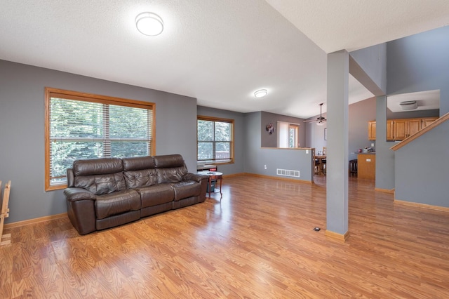 living room with a textured ceiling, light hardwood / wood-style flooring, and lofted ceiling