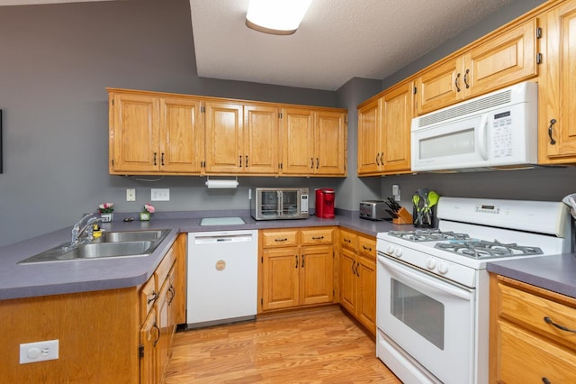 kitchen with a textured ceiling, light hardwood / wood-style floors, white appliances, and sink