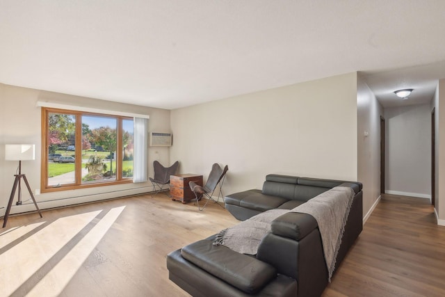 living room featuring hardwood / wood-style floors, an AC wall unit, and a baseboard heating unit