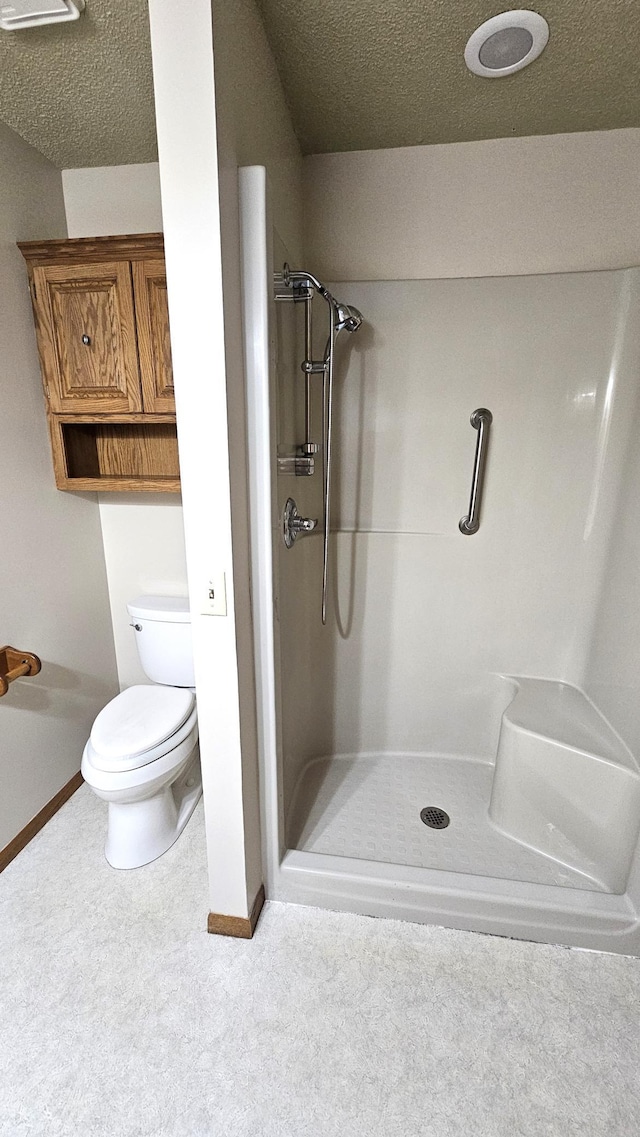 bathroom featuring toilet, a textured ceiling, and a shower