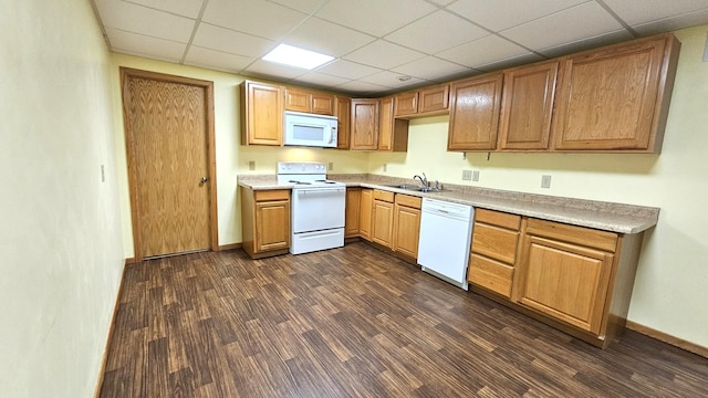 kitchen with sink, white appliances, dark wood-type flooring, and a paneled ceiling