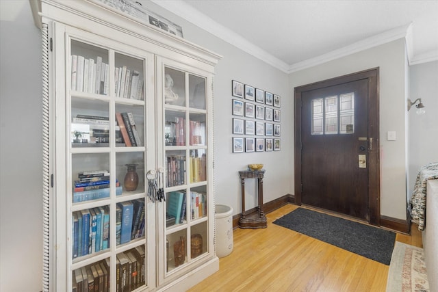 entryway with crown molding, wood finished floors, and baseboards