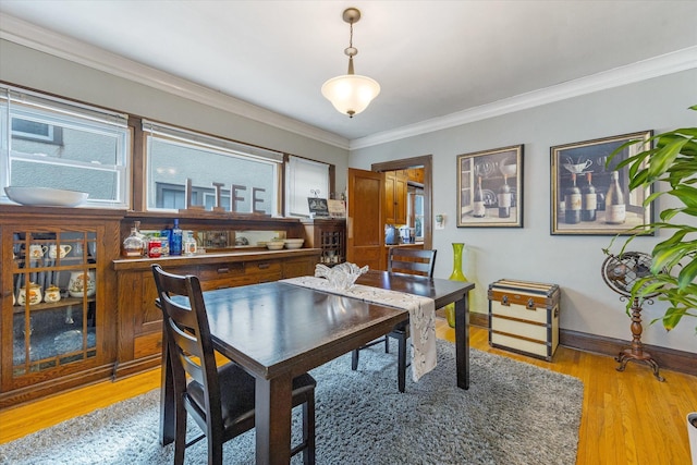 dining room featuring light wood-style flooring, crown molding, and baseboards