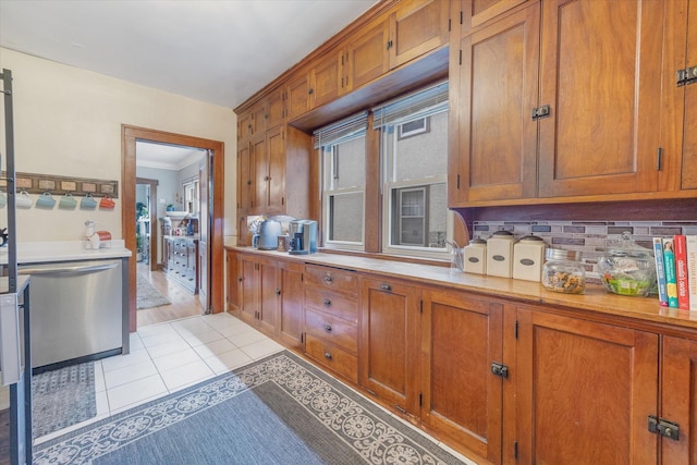 kitchen with stainless steel dishwasher, light countertops, and light tile patterned flooring