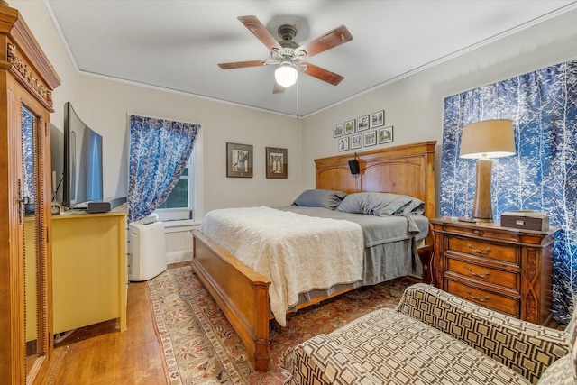 bedroom featuring baseboards, crown molding, ceiling fan, and wood finished floors