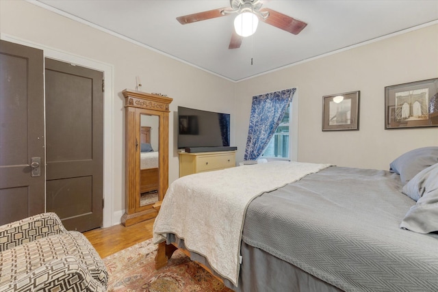 bedroom with crown molding, light wood-type flooring, and a ceiling fan