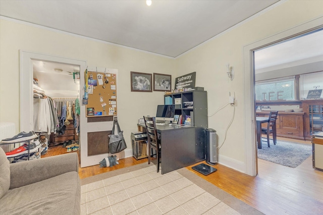 office area featuring baseboards, wood finished floors, radiator heating unit, and crown molding