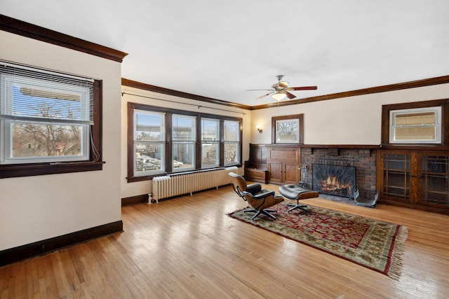 living area with wood finished floors, radiator heating unit, a fireplace, and ornamental molding