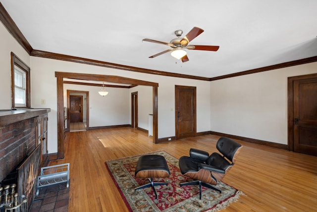 living room with light wood-type flooring, baseboards, a fireplace, and crown molding