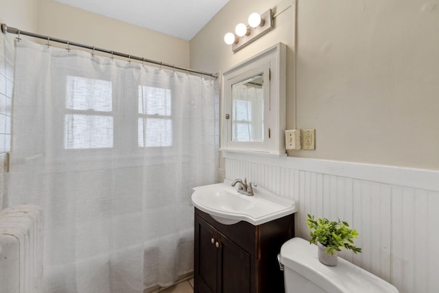 full bath featuring vanity, toilet, wainscoting, and radiator heating unit