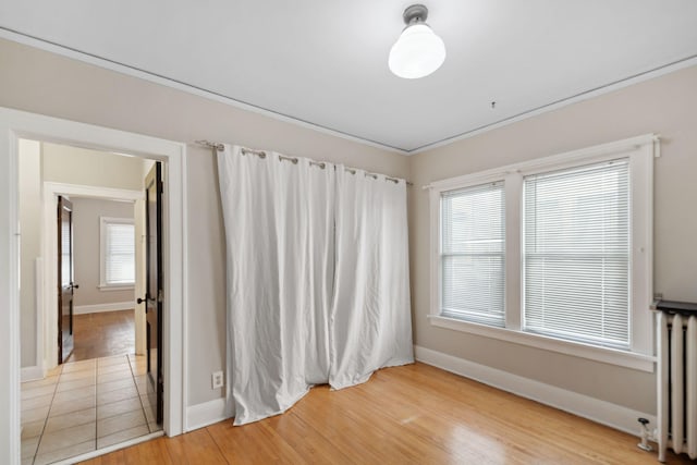 unfurnished room with light wood-style flooring, radiator heating unit, and baseboards