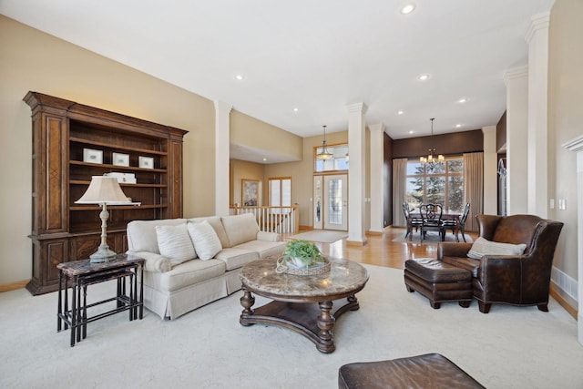 carpeted living room with a chandelier and ornate columns