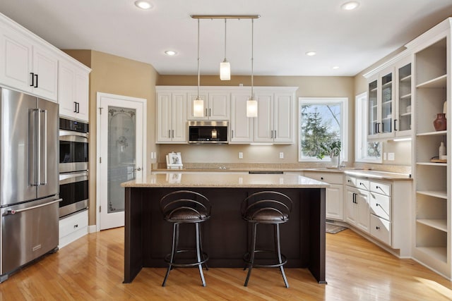 kitchen featuring a kitchen bar, a center island, white cabinets, and appliances with stainless steel finishes