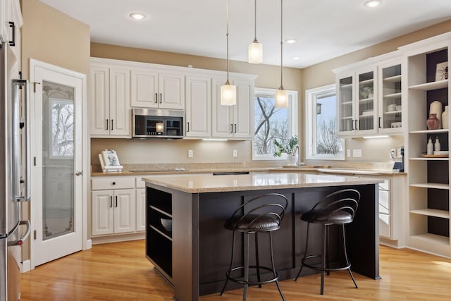 kitchen with appliances with stainless steel finishes, a center island, white cabinets, and a breakfast bar