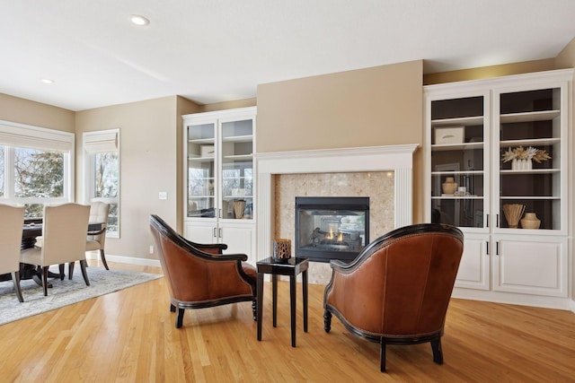 sitting room featuring a multi sided fireplace and light hardwood / wood-style flooring