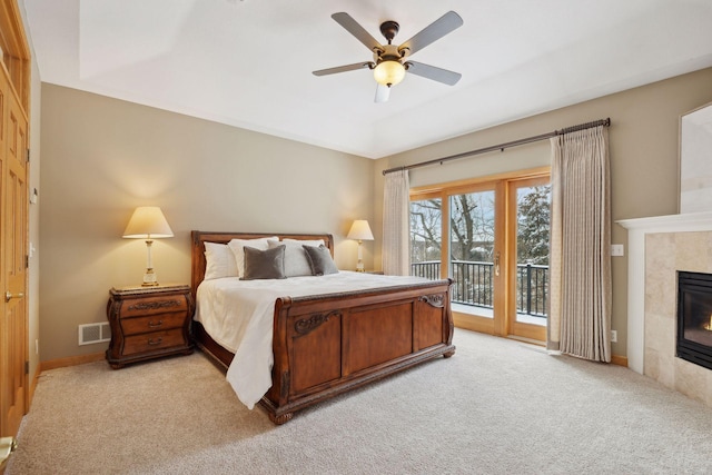 bedroom with light carpet, access to outside, a tile fireplace, and ceiling fan