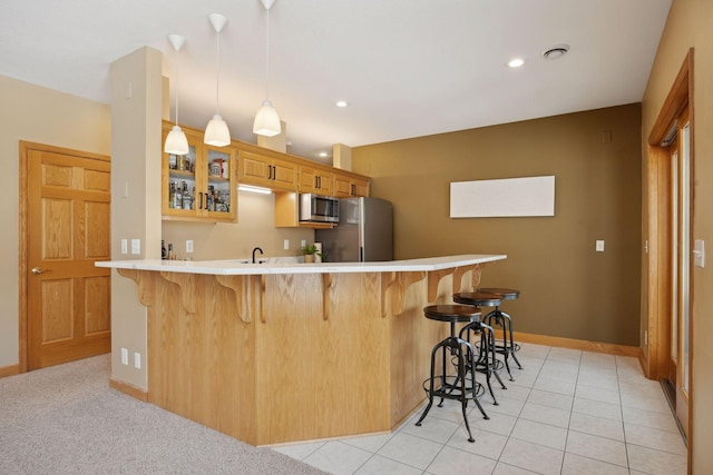 kitchen with sink, a breakfast bar area, appliances with stainless steel finishes, hanging light fixtures, and kitchen peninsula