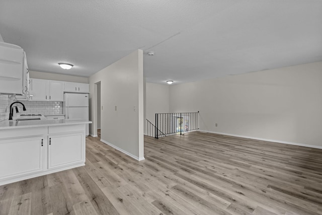 kitchen with sink, tasteful backsplash, white fridge, light hardwood / wood-style floors, and white cabinets