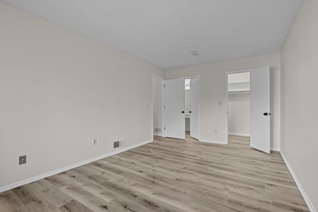 unfurnished bedroom featuring a spacious closet and light wood-type flooring