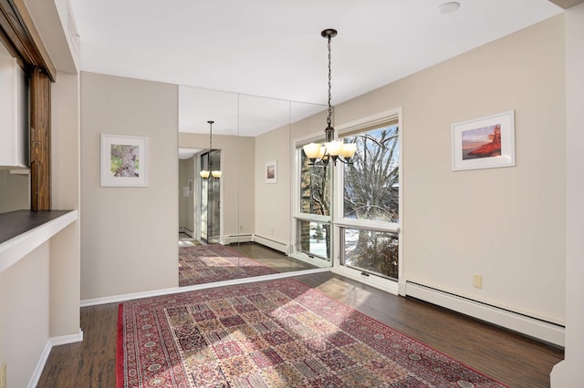 unfurnished dining area with a notable chandelier, dark hardwood / wood-style flooring, and a baseboard radiator