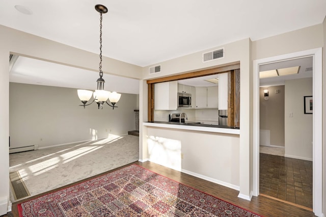 kitchen with a baseboard heating unit, an inviting chandelier, white cabinetry, hanging light fixtures, and appliances with stainless steel finishes